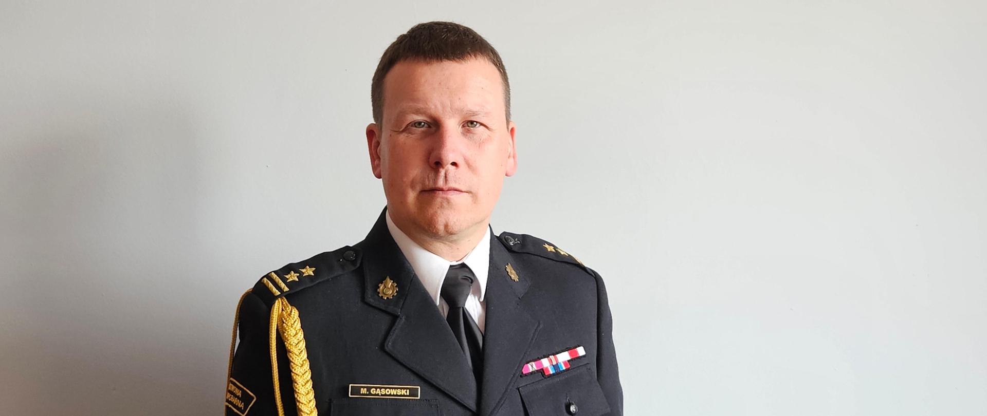 Zdjęcie portretowe p.o. Komendanta Miejskiego PSP w Siemianowicach Śląskich bryg. Marcina Gąsowskiego w mundurze wyjściowym na jasnym tle