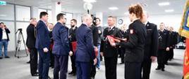 Wojewoda pomorski, sekretarz stanu w Ministerstwie Infrastruktury, prezes Wojewódzkiego Funduszu Ochrony Środowiska i Gospodarki Wodnej w Gdańsku oraz pomorski komendant wojewódzki Państwowej Straży Pożarnej wręczają promesy dla druhów ochotniczych straży pożarnych. Dokumenty podaje strażak Komendy Wojewódzkiej Państwowej Straży Pożarnej. 