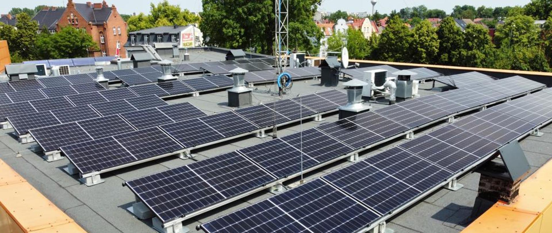 Zdjęcie przedstawia dach budynku Komendy Powiatowej PSP W Wolsztynie, a na nim panele fotowoltaiczne, widok od boku. 