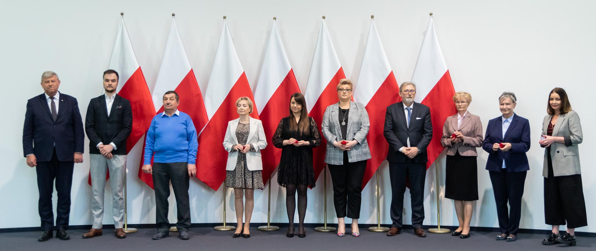 Kilka osób stojących na tle flag