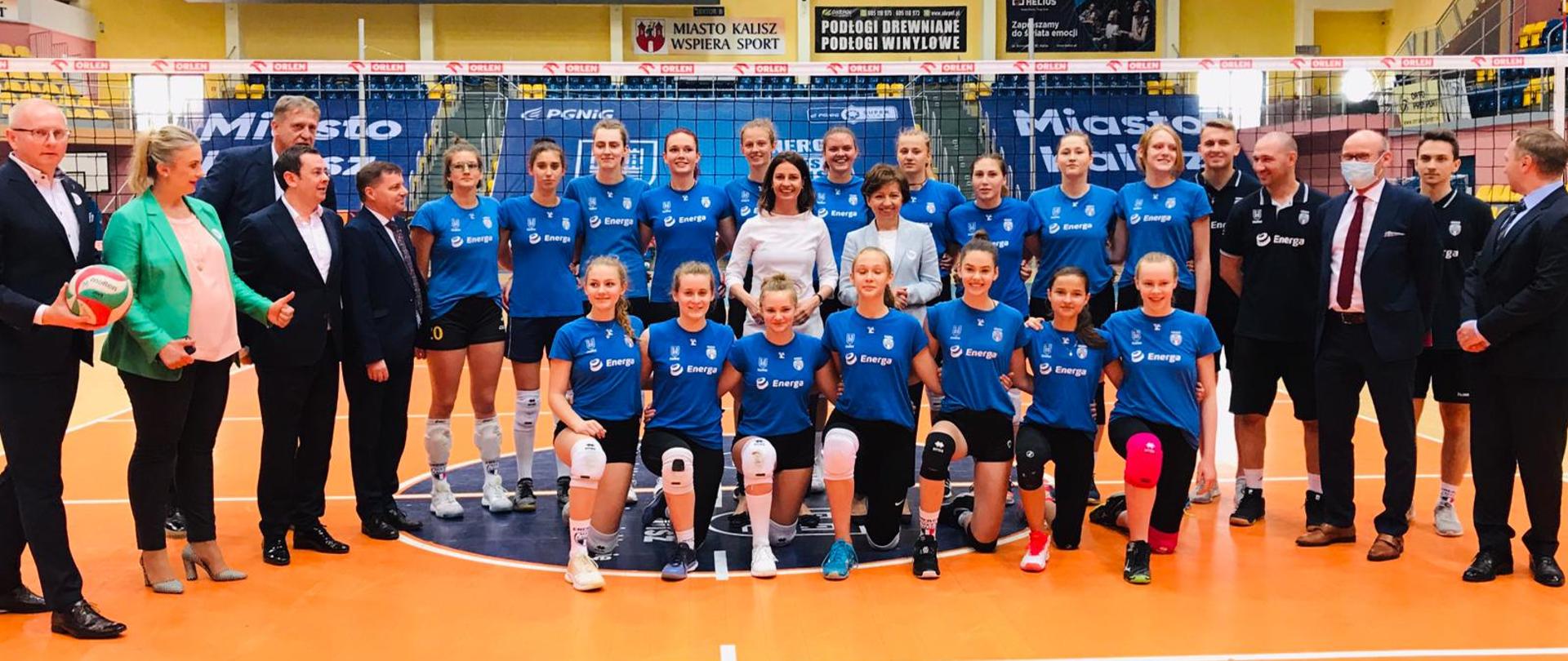 Wspólne zdjęcie siatkarek na hali sportowej wraz z Minister Danutą Dmowską-Andrzejuk