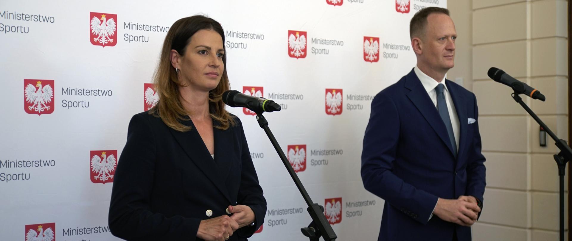 Pani Minister Sportu Danuta Dmowska-Andrzejuk i Prezes Zarządu Totalizatora Sportowego Olgierd Cieślik stoją razem przy mikrofonach. W tle ścianka konferencyjna Ministerstwa Sportu.