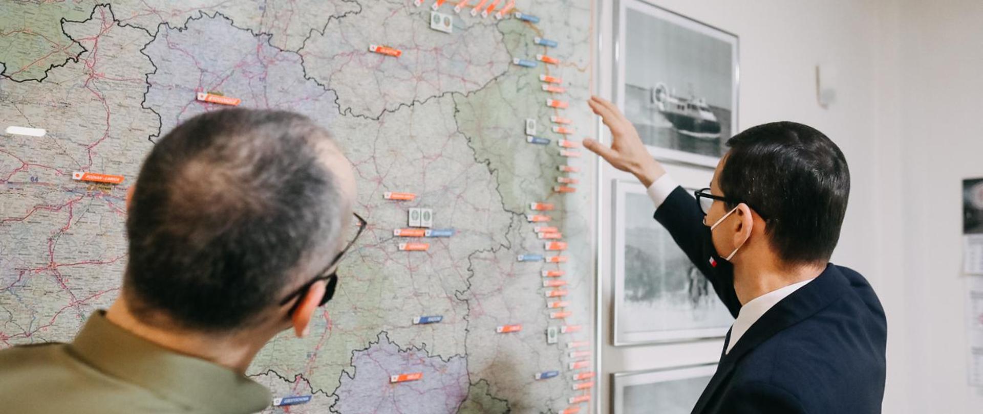 Premier, komendant Straży Granicznej stoją przy mapie Polski.
