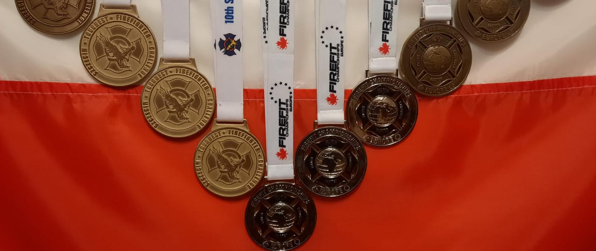 Zdjęcie przedstawia 10 medali eksponowanych na fladze Polski.