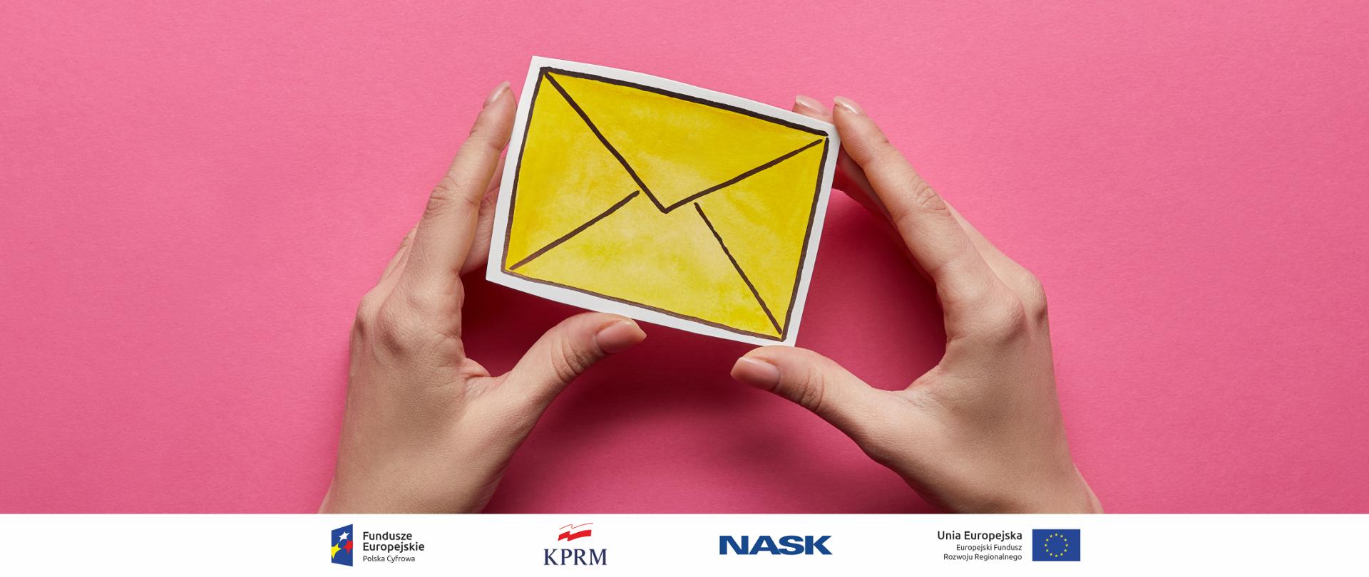 Różowe tło - na pierwszym planie kobiece dłonie trzymające rysunek żółtej koperty.