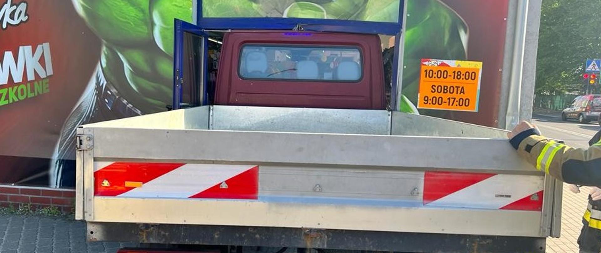 Zdjęcie przedstawia auto, które wjechało w drzwi sklepu, uszkadzając je.