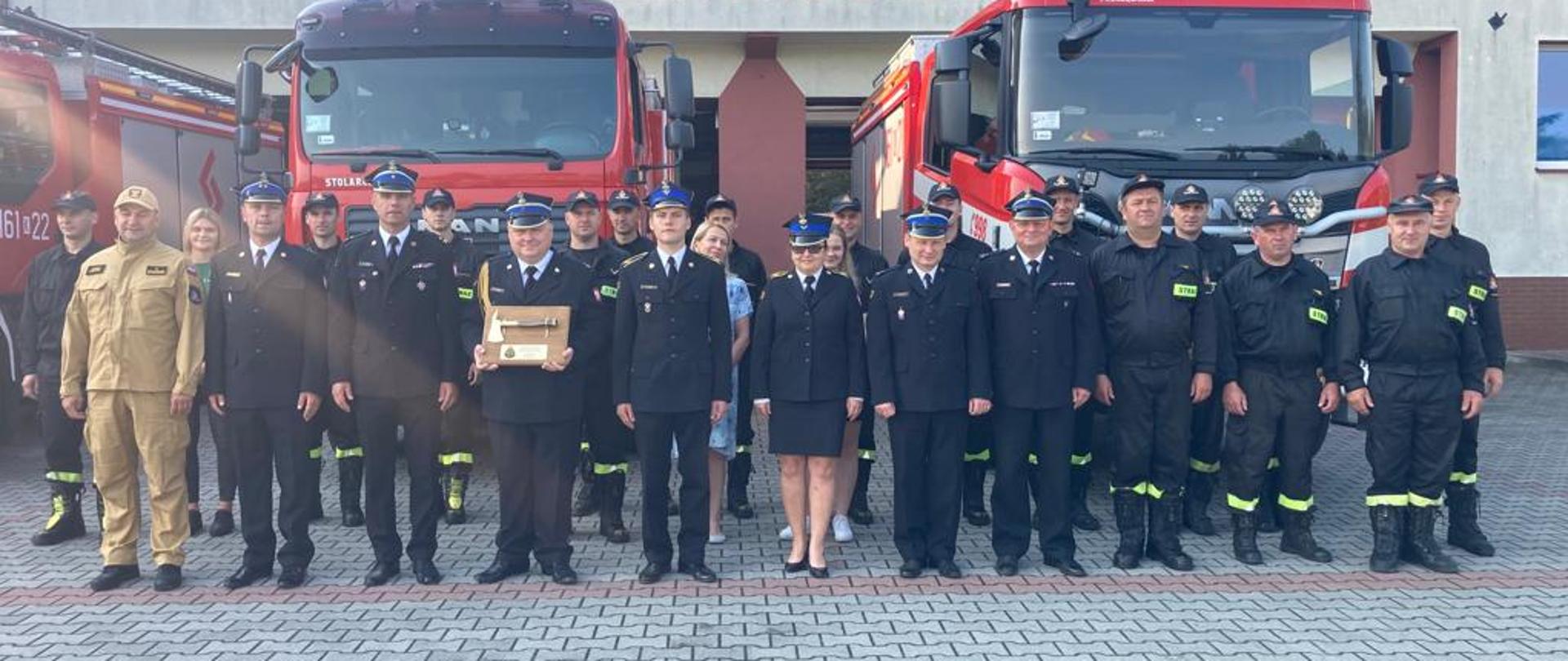 Na zdjęciu widoczni funkcjonariusze KP PSP Miechów na tle samochodów pożarniczych oraz budynku JRG Miechów
