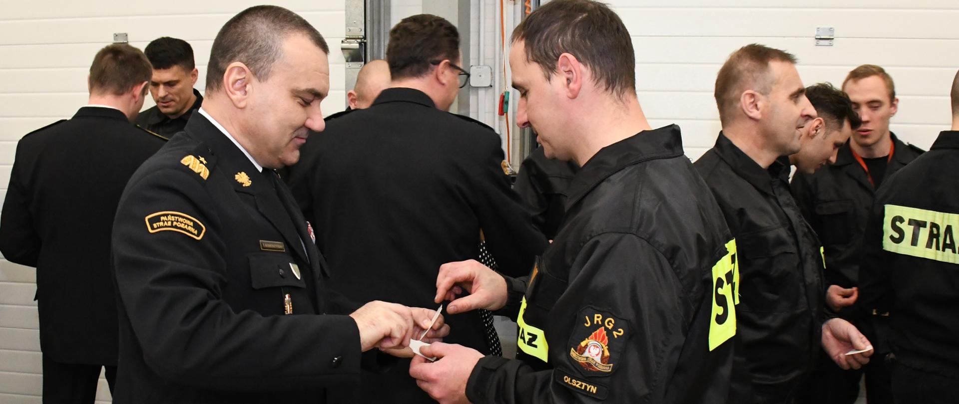 Komendant Wojewódzki przełamuje się opłatkiem ze strażakiem z JRG 2 Olsztyn.