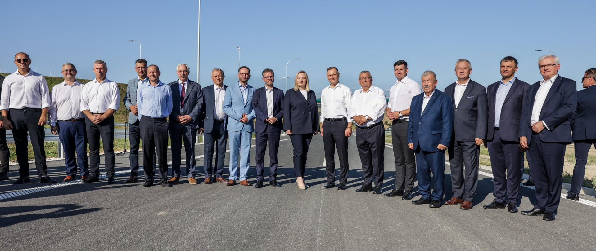 Wiceminister funduszy i polityki regionalnej Ewelina Owczarska na otwarciu odcinka drogi ekspresowej S7 Moczydło-Miechów, wraz z prezydentem PR, ministrem Infrastruktury i innymi uczestnikami uroczystości stoją na oddawanej do użytku drodze 