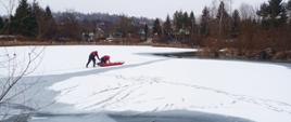 Na zdjęciu strażacy ćwiczą na zalodzonym zbiorniku wodnym