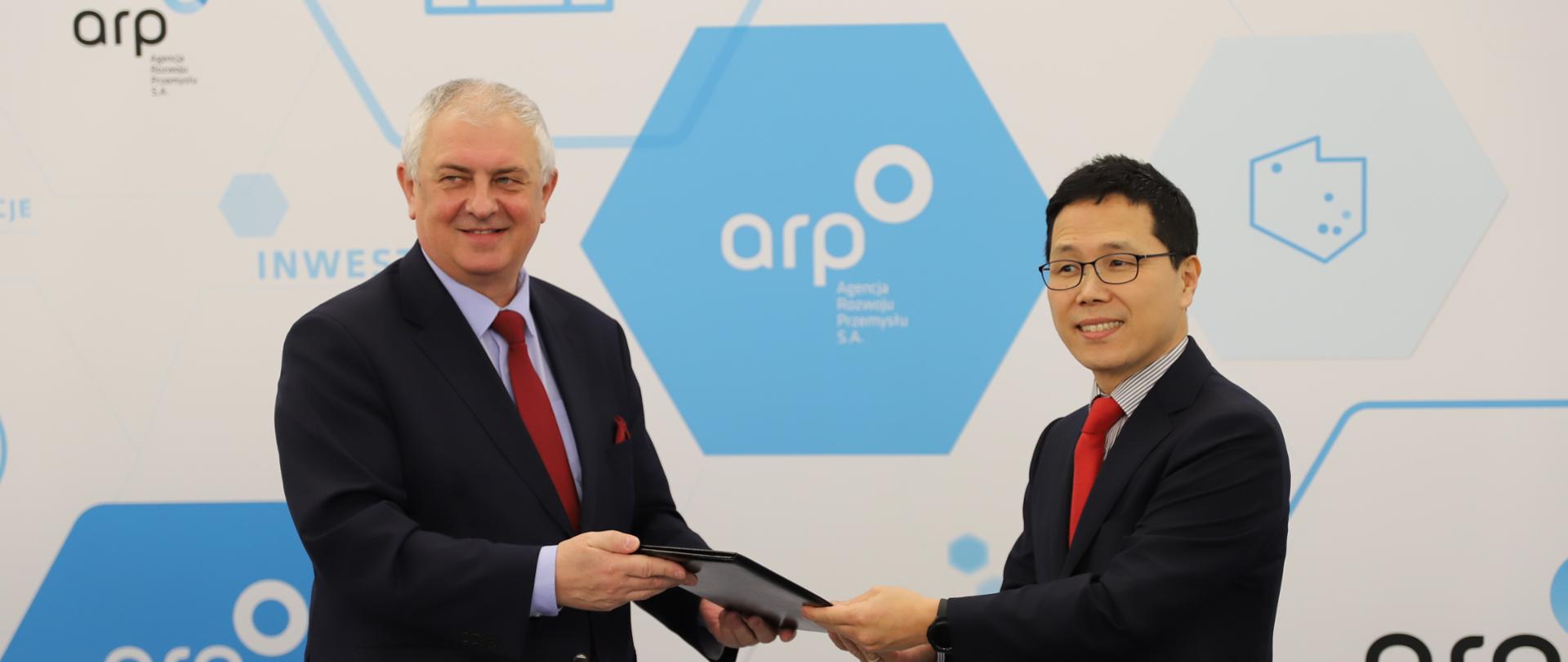 Wiceminister Grzegorz Piechowiak i dyrektor generalny południowokoreańskiej firmy Enchem Poland trzymają w rękach dokument potwierdzający wsparcie inwestycji. 
