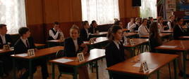 Młodzież na egzaminie siedząca w łąwkach