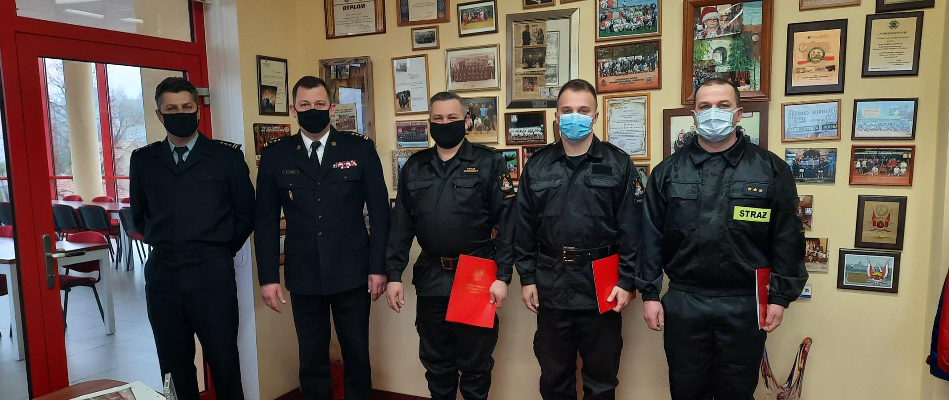 Na zdjęciu widać trzech strażaków oraz dwóch komendantów którzy mianują na wyższe stanowiska służbowe 