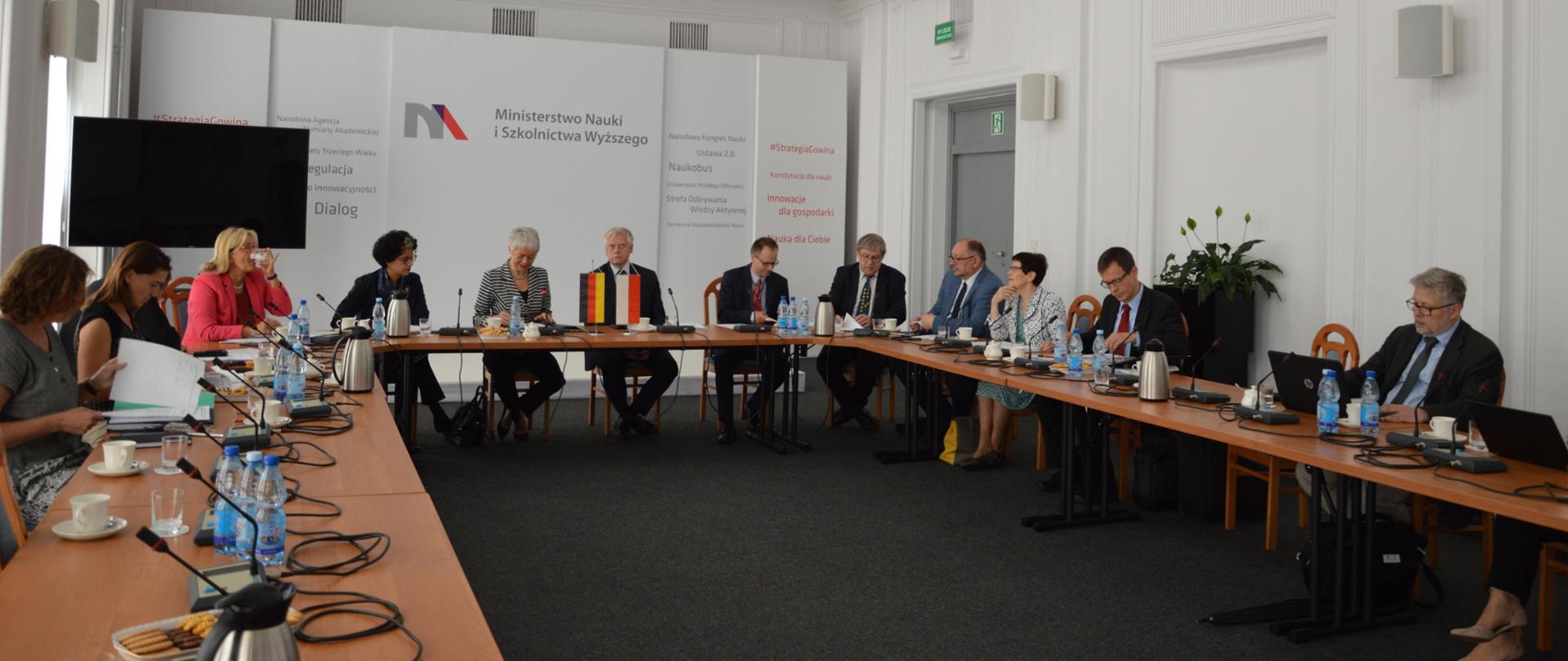 Sala w MNiSW, uczestnicy spotkania siedzą przy stołach ustawionych w prostokąt