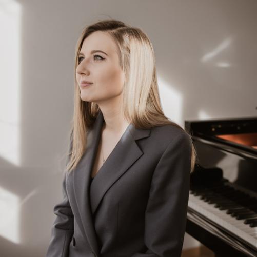 Postać kobiety przy fortepianie.