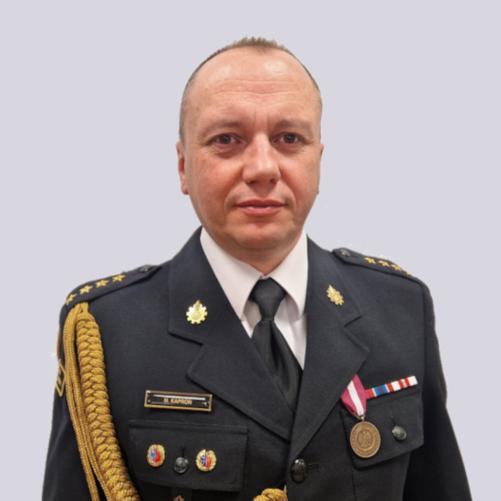 Zdjęcie portretowe p.o. zastępca komendanta st. kpt. Marcin Kaproń na jasnym tle w mundurze galowym