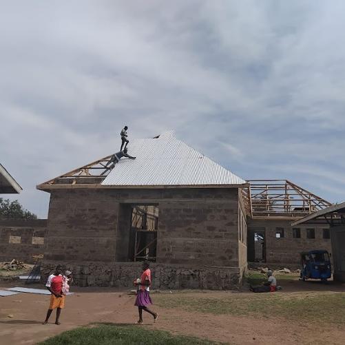 Budynki w czasie budowy, przed budynkiem stoi kilka osób