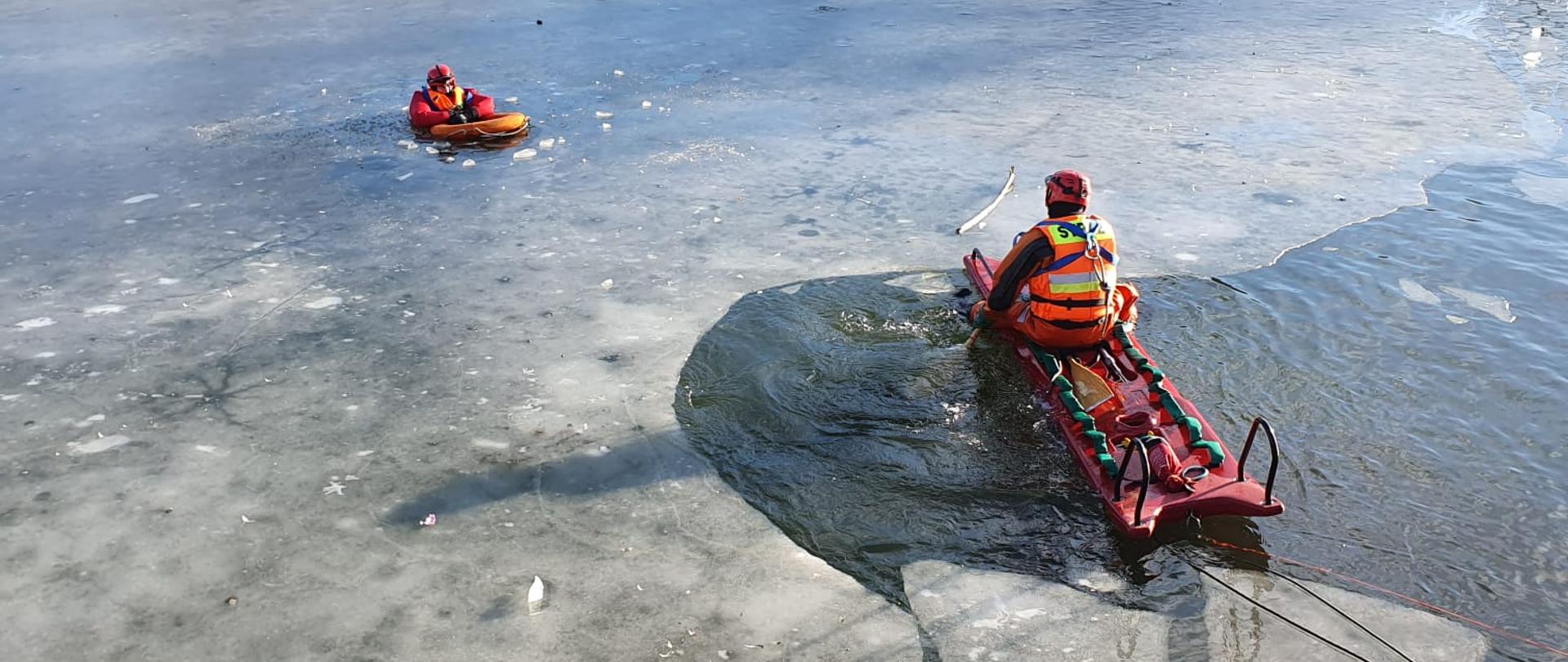 Strażak na saniach lodowych podejmuje poszkodowanego
