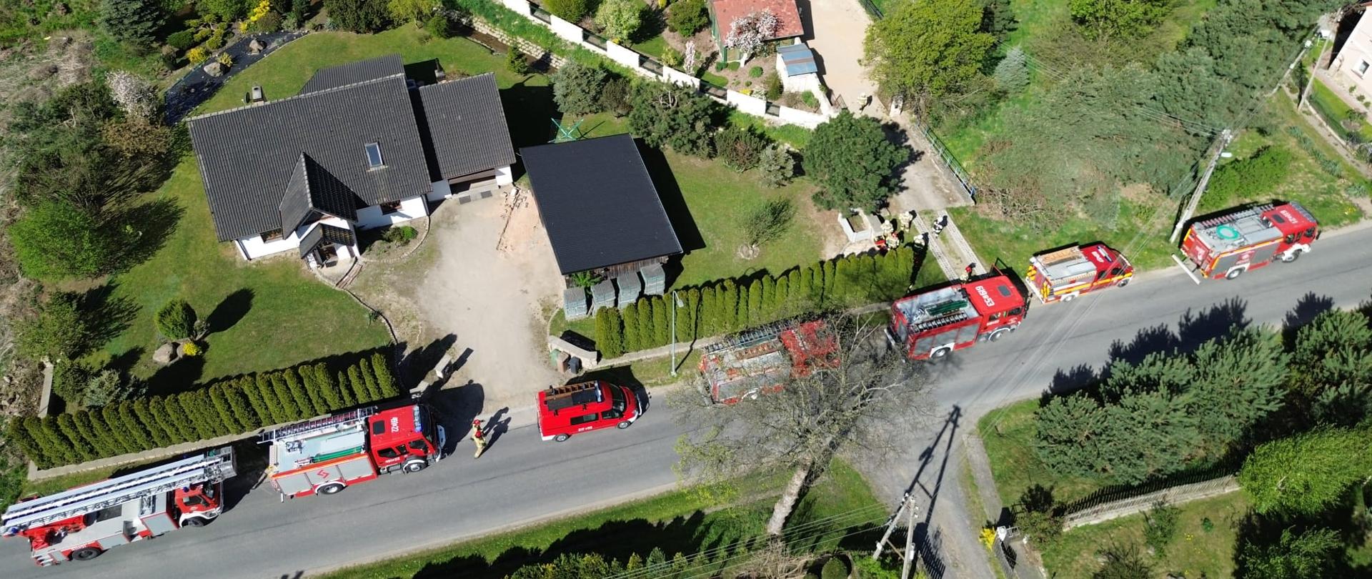 widok z lotu ptaka, wzdłuż ulicy stoją samochody pożarnicze, w pobliżu kilka budynków mieszkalnych