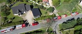 widok z lotu ptaka, wzdłuż ulicy stoją samochody pożarnicze, w pobliżu kilka budynków mieszkalnych