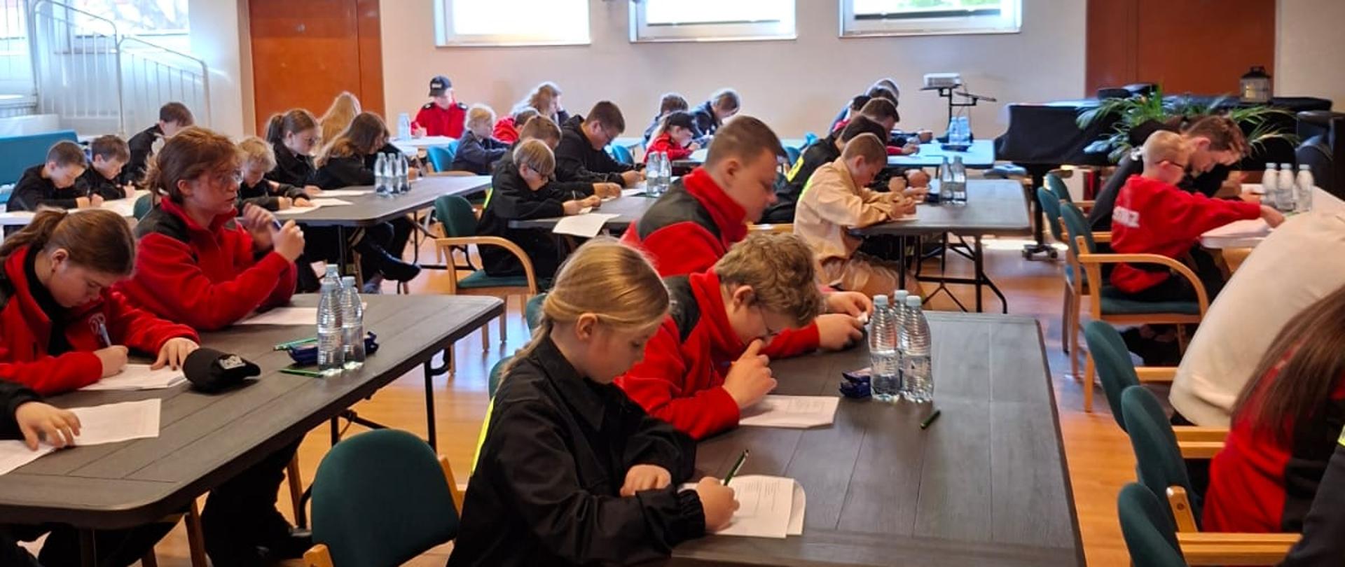 Ogólnopolski Turniej Wiedzy Pożarniczej etap pisemny. Dzieci i młodzież rozwiązuje test wiedzy pożarniczej