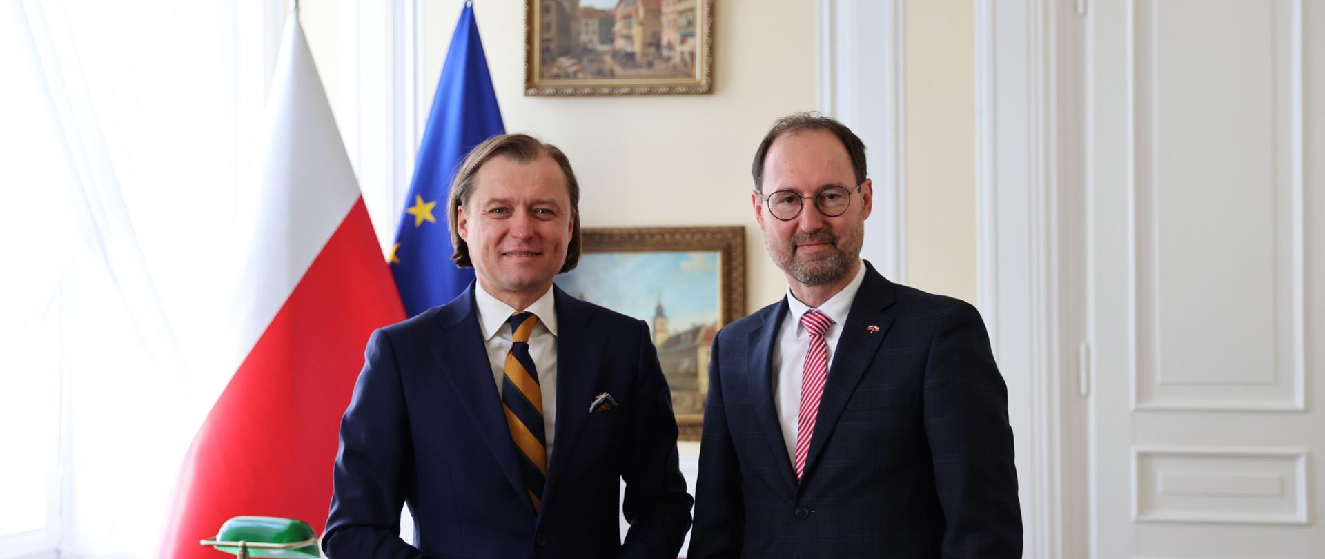 Na zdjęciu dwóch mężczyzn. W tle flaga Polski oraz Unii Europejskiej 