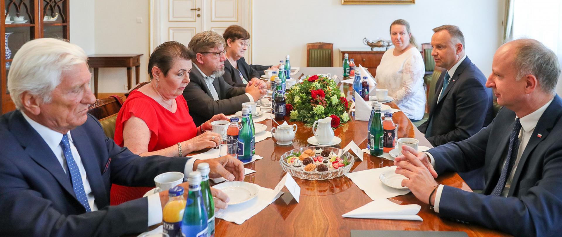 Zdjęcie w poziomie. Uczestnicy spotkania siedzą wokół stołu.