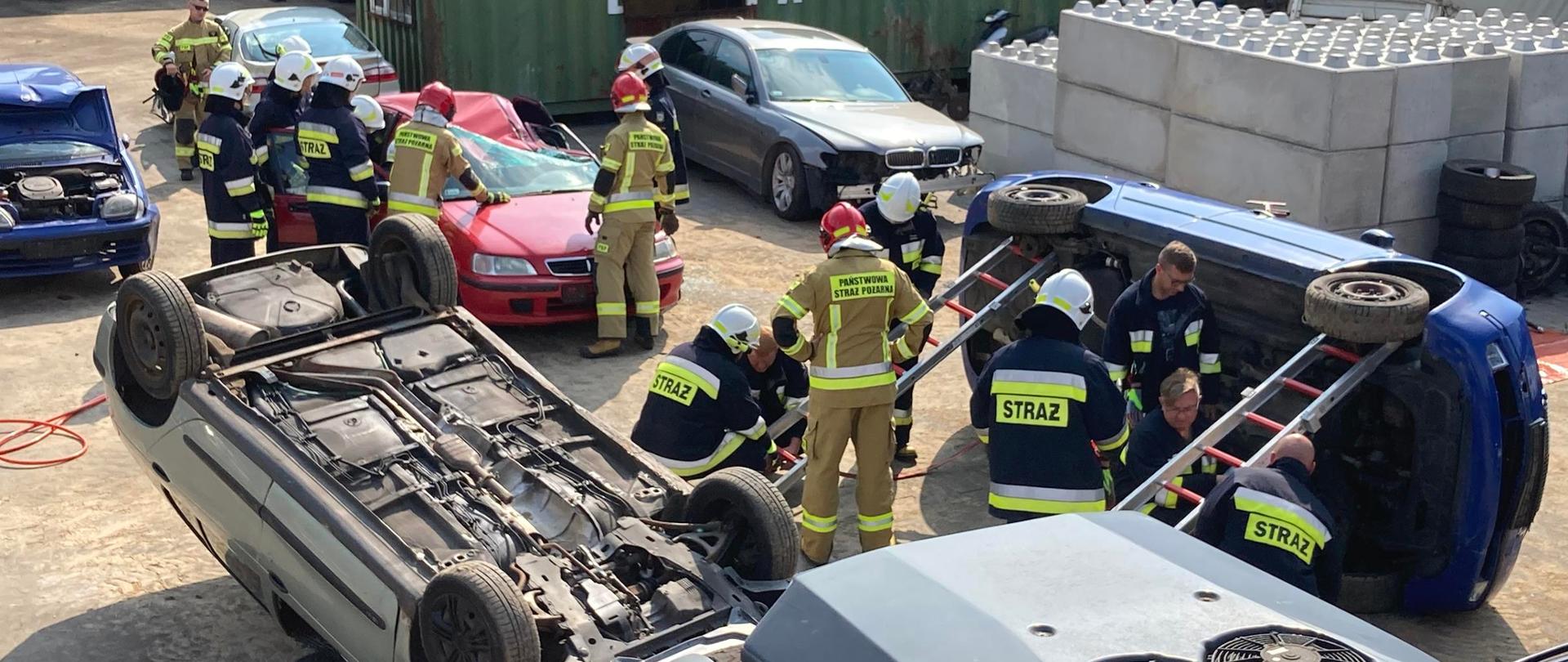 Zdjęcie przedstawia wraki pojazdów, sprzęt hydrauliczny oraz ćwiczących strażaków.