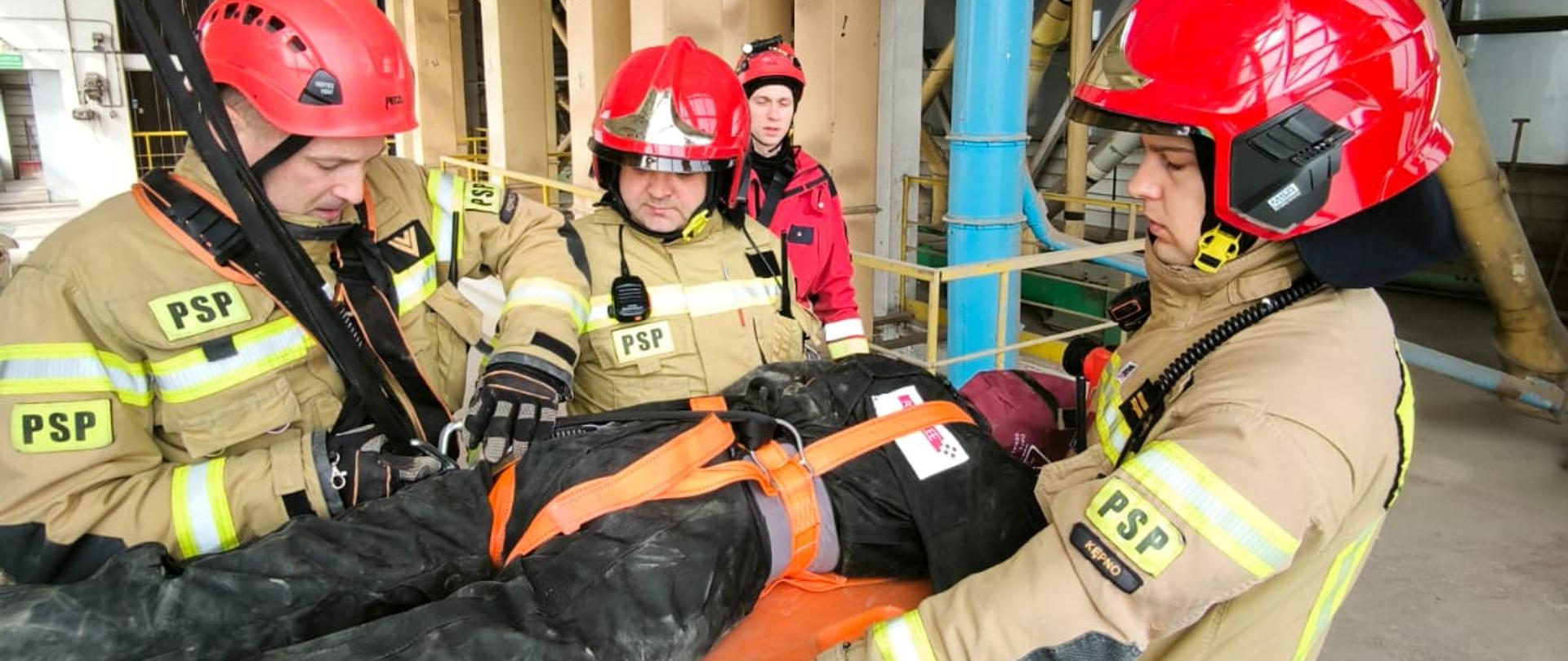 widoczni strażacy podczas ewakuacji manekina technikami linowymi.