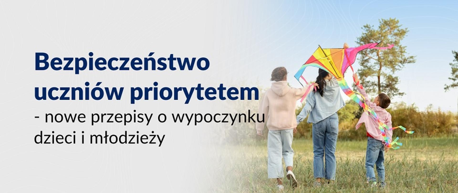 Troje dzieci z latawcem na łące. Napis: Bezpieczeństwo uczniów priorytetem - nowe przepisy o wypoczynku dzieci i młodzieży
