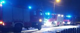 Samochody ratowniczo gaśnicze z włączonymi sygnałami świetlnymi biorące udział w akcji gaśniczej.