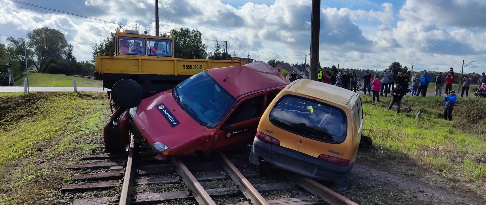 Zdjęcie przedstawia dwa samochody na torach po uderzeniu w drezynę
