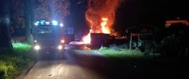 Jest noc, po lewej widać samochód strażacki, po prawej widać pożar opon