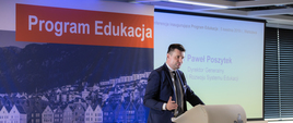 Paweł Poszytek, dyrektor generalny Fundacji Rozwoju Systemu Edukacji przy mównicy podczas przemówienia, w tle nazwa "Program Edukacja".