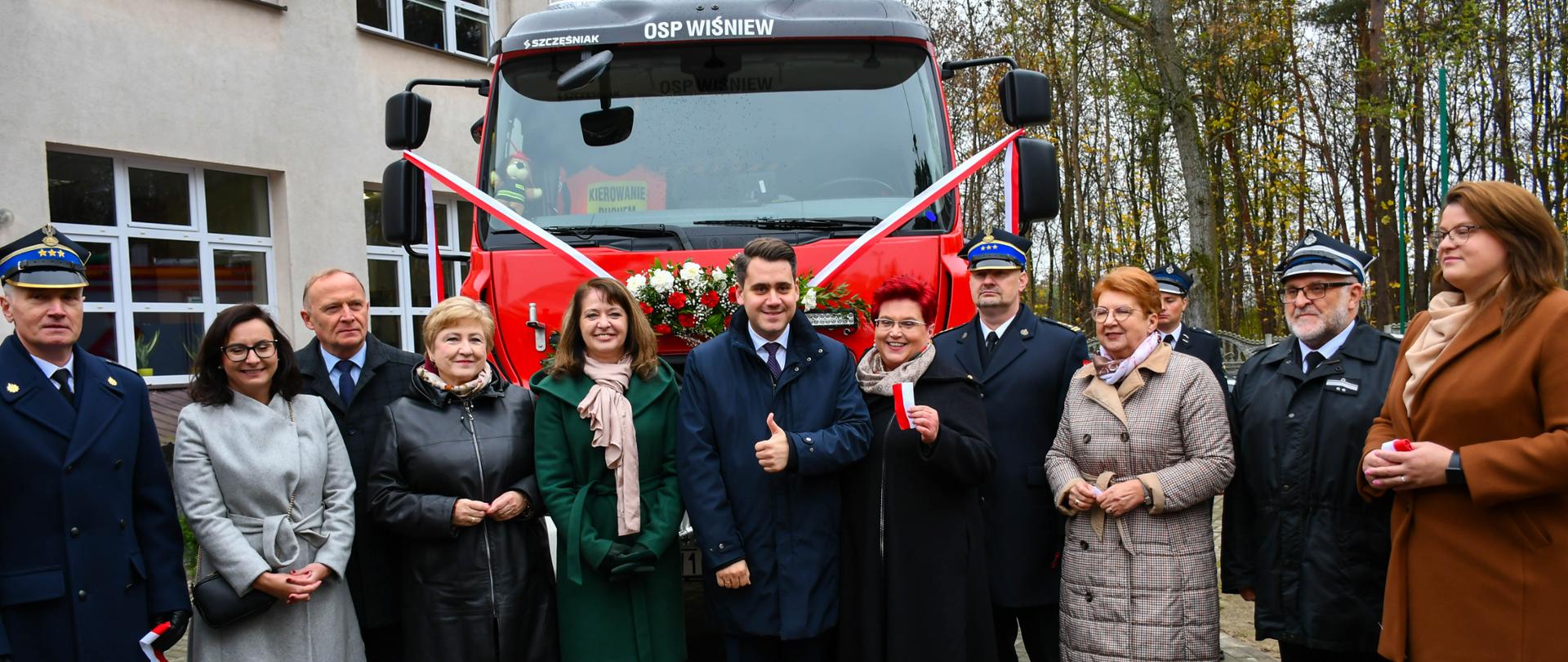 zaproszeni parlamentarzyści i inni goście na tle nowego samochodu pożaraniczego