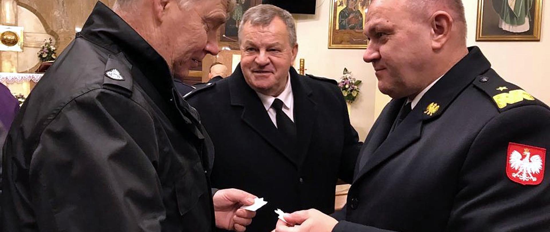 Zdjęcie zrobione wewnątrz kościoła, czas uroczystego spotkania wigilijnego strażaków oraz Kapelanów Straży Pożarnych Województwa Podkarpackiego. Strażacy dzielą się opłatkami.