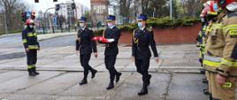 Zdjęcie przedstawia funkcjonariuszy PSP niosących flagę Polski