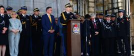 Komendant główny PSP przemawia do mikrofonu na scenie, za nim stoją zaproszeni goście