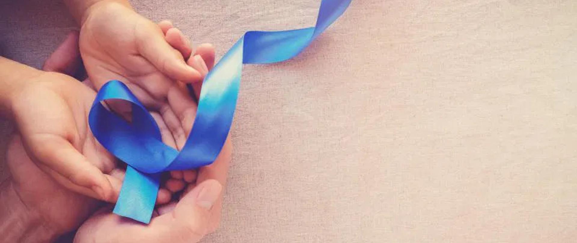 w dłoniach niebieska wstążka symbol - Miesiąca Świadomości Raka Jelita Grubego.