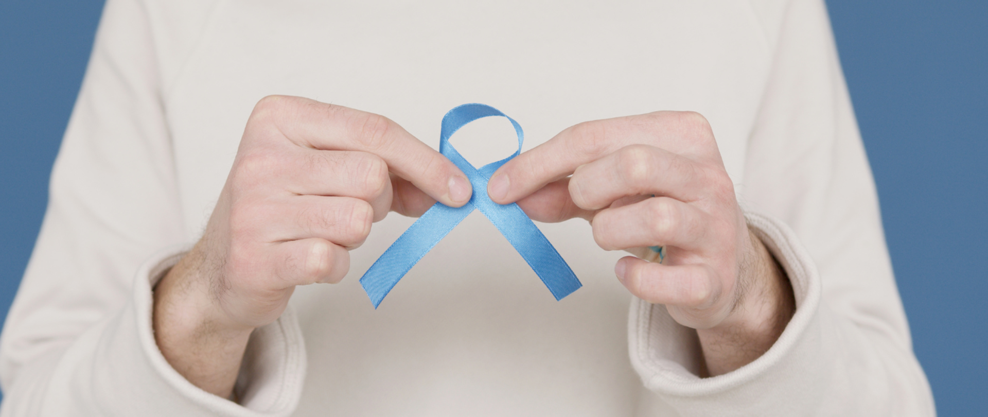 Mężczyzna trzyma niebieską wstążeczkę - symbol raka prostaty