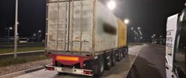Od lewej: wieloosiowy zespół pojazdów ciężarowych z dwoma kontenerami 20-stopowymi stoi w zatoce kontrolnej. Po jego prawej stronie jest zaparkowany oznakowany furgon mazowieckiej Inspekcji Transportu Drogowego.