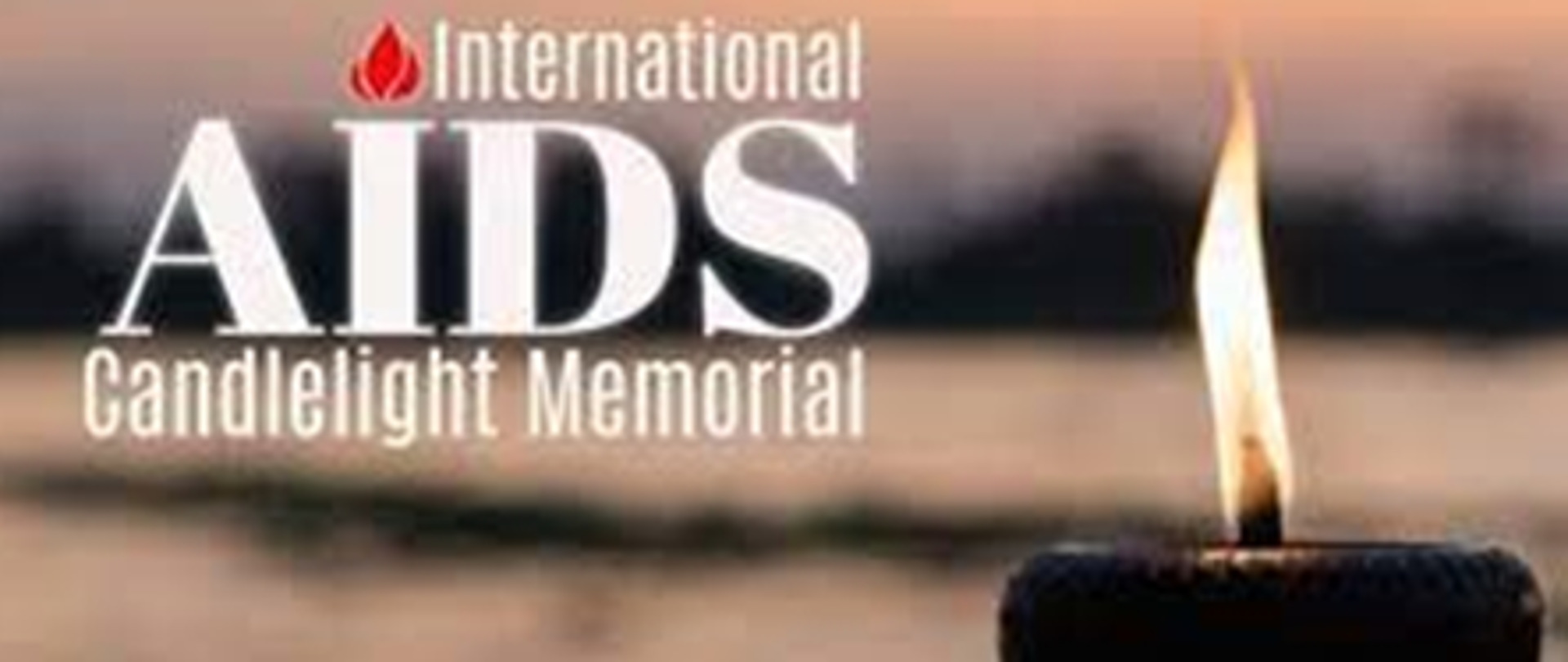 Grafika podzielona na dwie części, po lewej napisy białą czcionką: International AIDS Candlelight Memorial i na pierwszym planie płonący znicz. Natomiast po prawej płonąca świeca w ludzkich dłoniach.