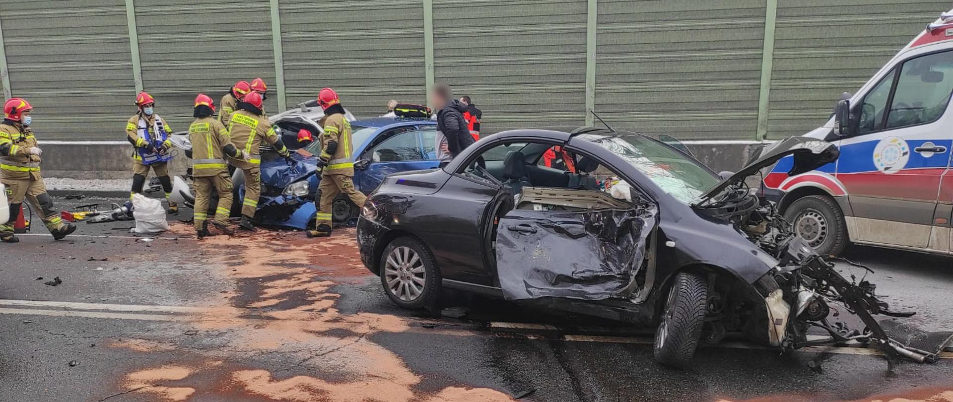 Strażacy przy użyciu sprzętu hydraulicznego uwalniają z pojazdu uwięzioną osobę.
