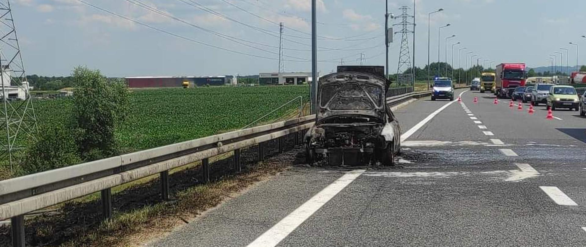 Na zdjęciu spalony samochód osobowy znajdujący się na pasie awaryjnym autostrady