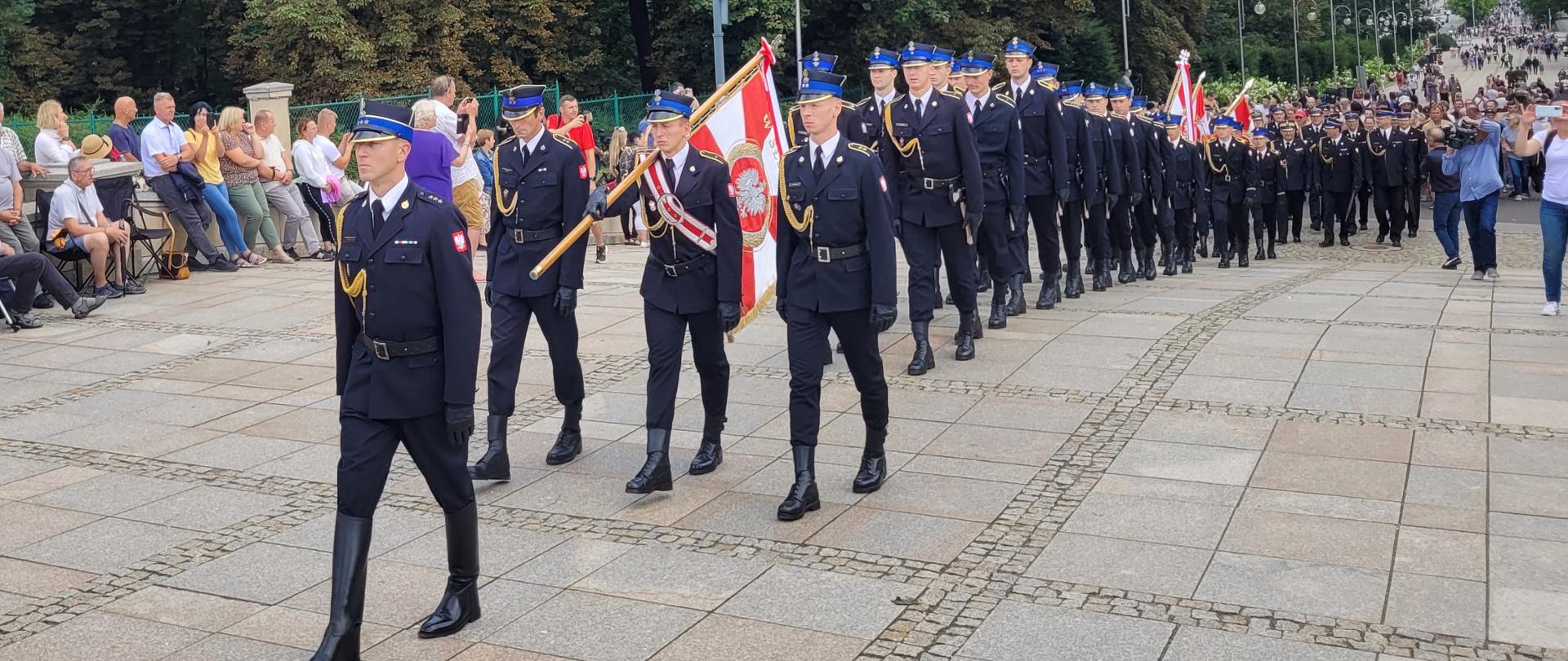 pod Jasną Górę podchodzi poczet sztandarowy Komendy Głównej PSP, kompania honorowa KW PSP w Katowicach oraz trzy poczty sztandarowe, za nimi komendanci oraz pozostali pielgrzymi 