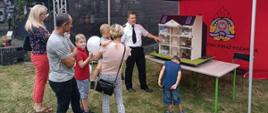 Na zdjęciu funkcjonariusz straży pożarnej prezentuje mobilny symulator zagrożeń pożarowych na dożynkach 