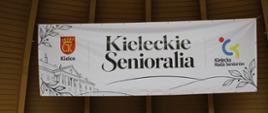 Baner z nazwą Kieleckie Senioralia zawieszony w muszli koncertowej Parku Miejskiego w Kielcach