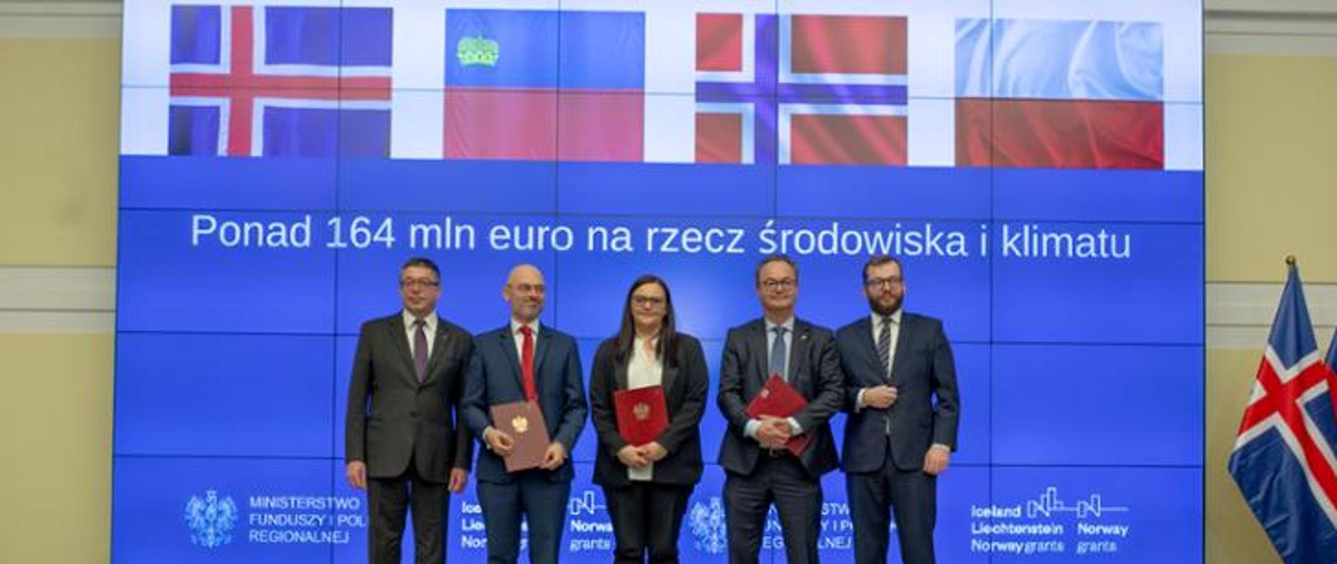 Photo with signed contracts, among them there is minister Jarosińska-Jedynak, ambassador of Norway to Poland Olav Mykelbust, minister Kurtyka and minister Puda. Behind them is the inscription over EUR 164 million for the environment and climate