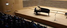 Pianista gra na fortepianie na scenie sali koncertowej PSM, z przodu publiczność siedzi na widowni