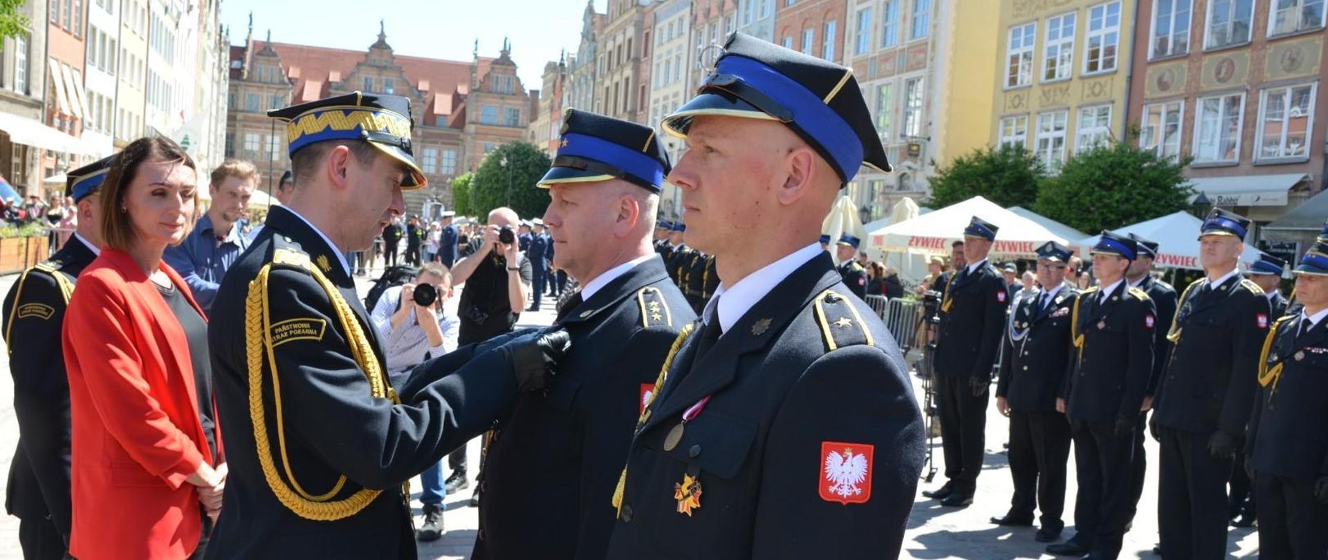 Komendant główny PSP dekoruje medalami zasłużonych strażaków.